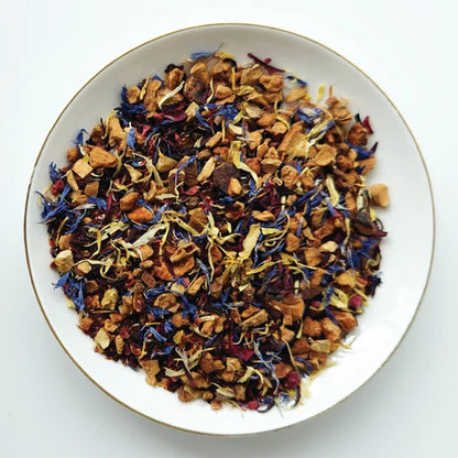 Mélange de tisane Belle Framboise Urbanithé — fleurs de bleuet, morceaux de fruits séchés et pétales colorés dans un bol blanc