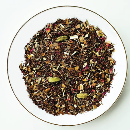 Vue de dessus du mélange sec Citron Exotique Urbanithé — rooibos, pétales de rose, citronnelle et épices dans assiette blanche à rebord doré