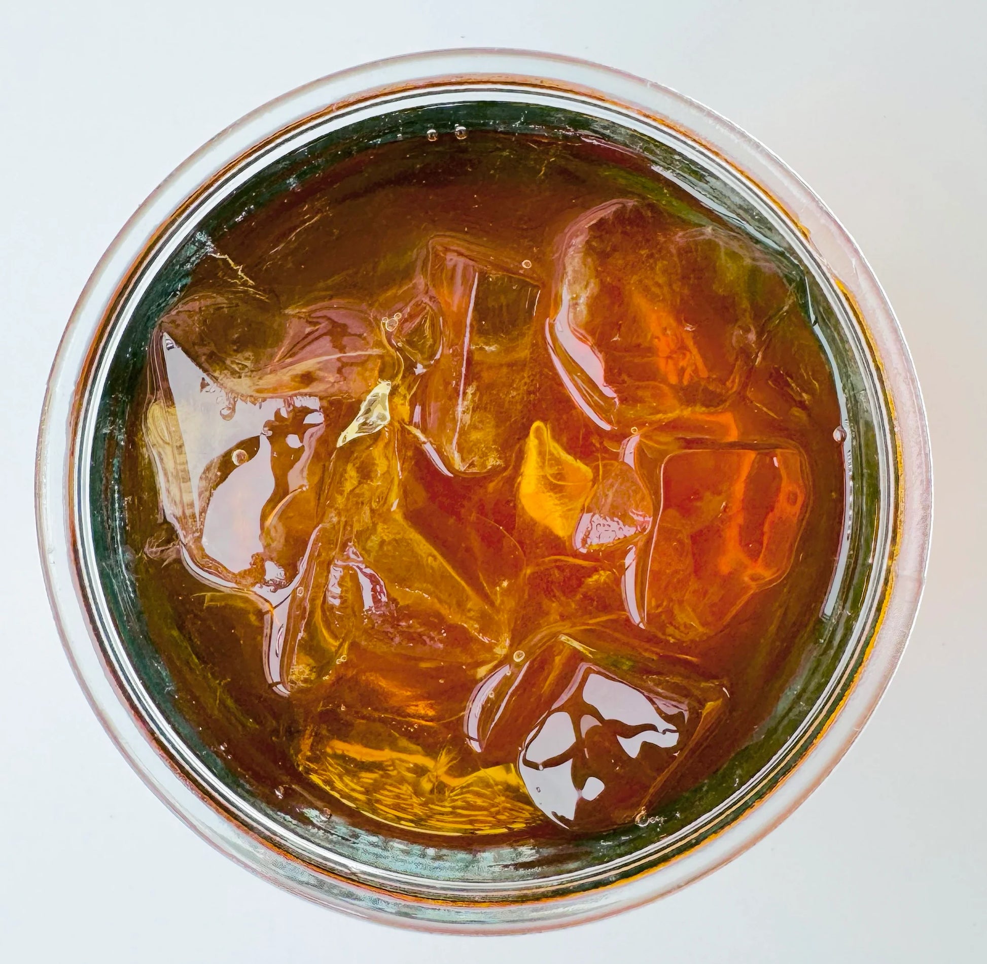 Vue de dessus d’un verre mason glacé contenant l’infusion à froid Citron Exotique Urbanithé — liquide ambré profond avec glaçons
