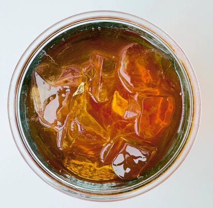Vue de dessus d’un verre mason glacé contenant l’infusion à froid Citron Exotique Urbanithé — liquide ambré profond avec glaçons