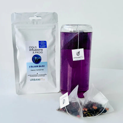 Bouteille transparente remplie d’Elixir Bleu Urbanithé violet intense avec sachet pyramidal, emballage argenté à côté