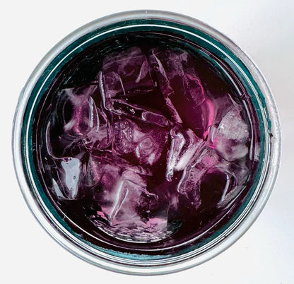 Vue de dessus d’un verre mason glacé contenant l’infusion à froid Elixir Bleu Urbanithé — liquide violet profond avec glaçons