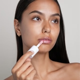 Femme appliquant l’huile à lèvres repulpante avec l’embout applicateur