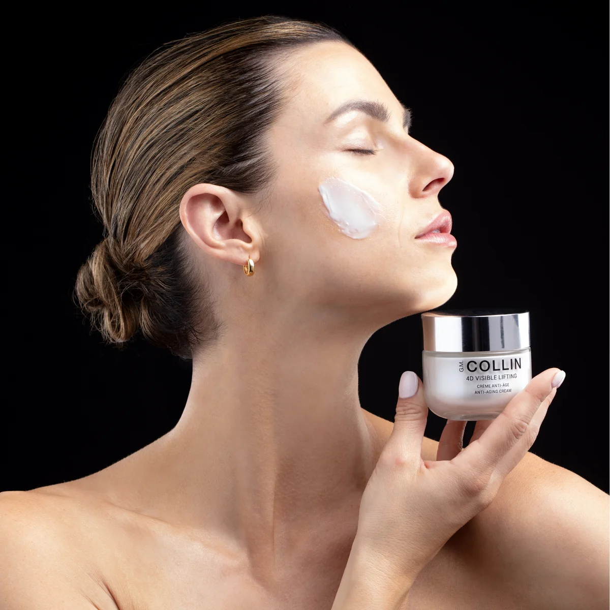 4D Visible Lifting Crème G.M. Collin - modèle tenant le pot crème avec application sur la joue fond noir - Spa Santé Le Nénuphar