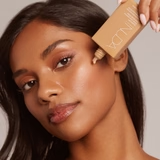 Femme tenant le flacon SolarGlow NUDA — écran solaire minéral FPS 30 pour tous les tons de peau — Spa Santé Le Nénuphar