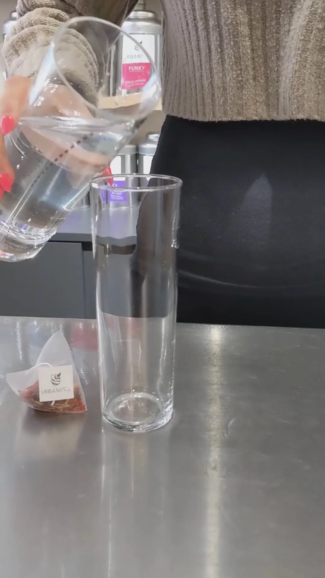 Préparation de l’infusion à froid Coco-Ananas Urbanithé — sachet pyramidal déposé dans un grand verre d’eau