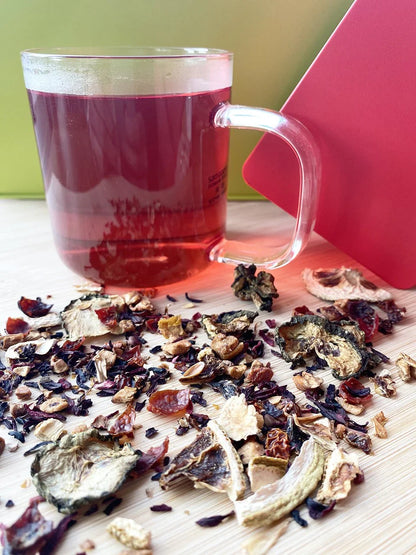 Mélange de plantes et fruits séchés de l’infusion L’Éclathé Urbanithé — concombre, tomate, hibiscus, orange devant une tasse rouge
