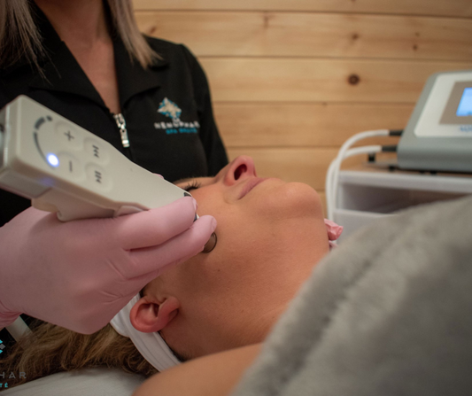 Liveflux - Visage au Spa Santé Le Nénuphar : technicienne portant des gants roses appliquant une pièce à main sur la joue d'une cliente allongée lors d'un soin du visage.