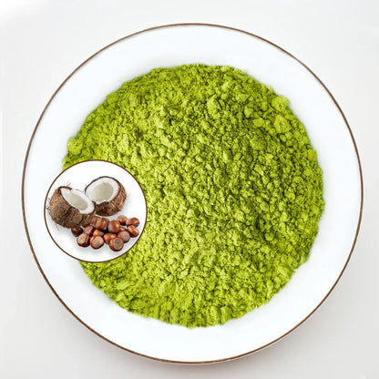 Vue de dessus poudre de matcha vert vif Urbanithé saveur coco-noisette dans assiette blanche bordée or avec médaillon noix de coco ouverte et noisettes, fond blanc