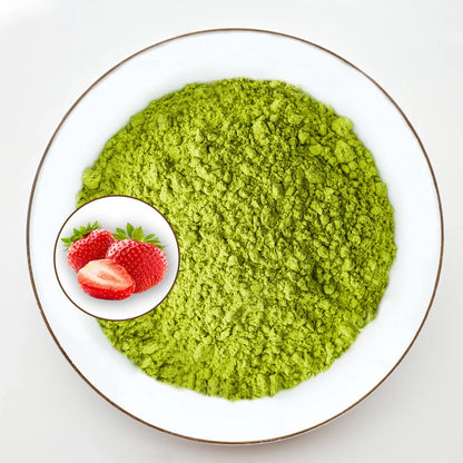 Vue de dessus poudre de matcha vert vif Urbanithé saveur fraise dans assiette blanche bordée or avec médaillon fraises rouges fraîches, fond blanc