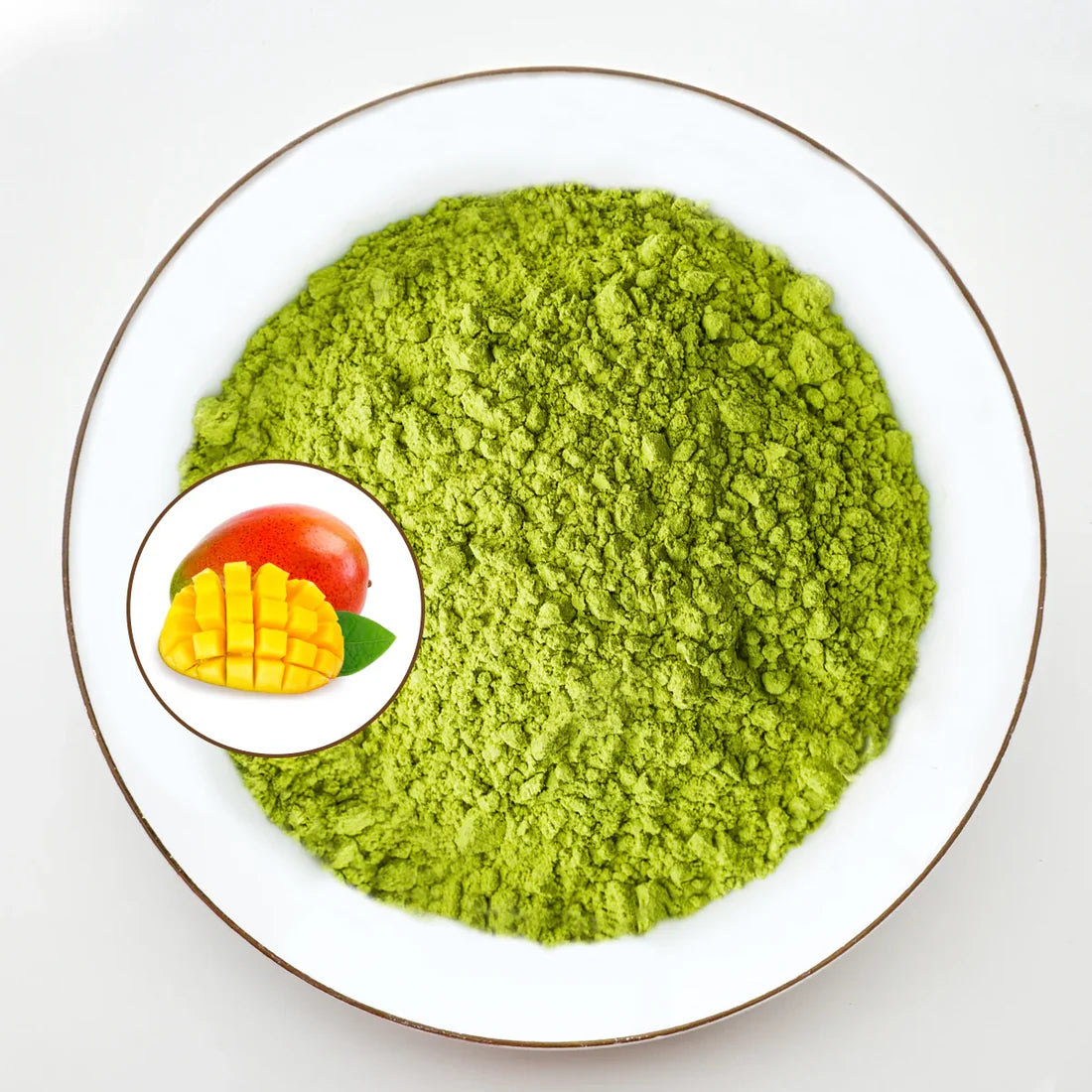 Vue de dessus poudre de matcha vert vif Urbanithé saveur mangue dans assiette blanche bordée or avec médaillon mangue coupée rouge et jaune, fond blanc