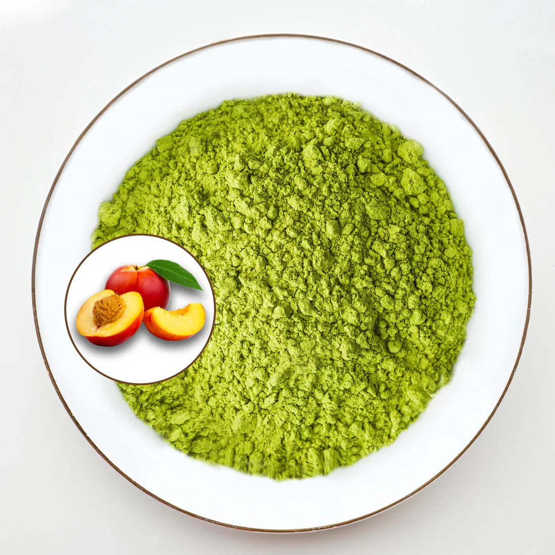 Vue de dessus poudre de matcha vert vif Urbanithé saveur pêche dans assiette blanche bordée or avec médaillon pêche coupée rouge et jaune, fond blanc