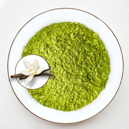 Vue de dessus poudre de matcha vert vif Urbanithé saveur vanille française dans assiette blanche bordée or avec médaillon fleur et gousse de vanille, fond blanc