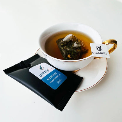 Vue de dessus du mélange sec No Stress Urbanithé — feuilles de mélisse, menthe, gingembre et pétales de calendula jaunes dans assiette blanche à rebord doré