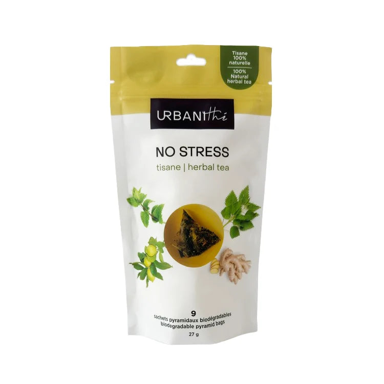 Vue de dessus d'une tasse blanche à anse dorée avec sachet pyramidal No Stress Urbanithé infusant dans liquide jaune doré, fond blanc