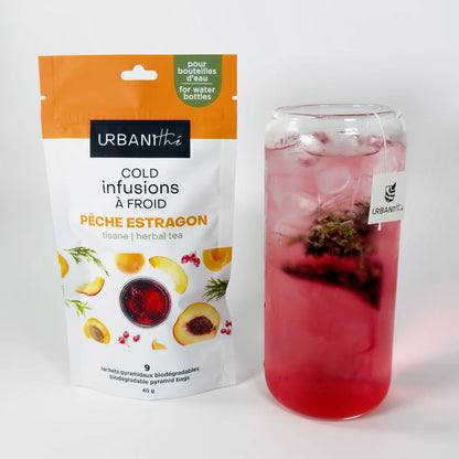 Emballage Pêche Estragon Urbanithé 25 sachets sur napperon tressé avec verre d'infusion rosée glacée, sachets pyramidaux sur assiette et cuillère dorée