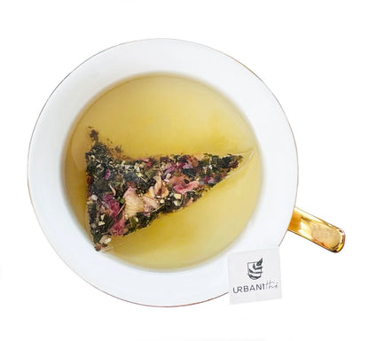 Sachet pyramidal Urbanithé Detox infusant dans une tasse à anse dorée — liquide vert-or, vue du dessus